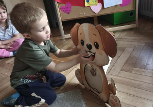 Dziecko sprawdza co pies może jeść wkładając wybrany produkt do psiej zabawki