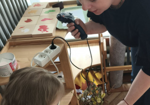 Dzieci przyklejają wydmuszki pod kontrola mamy Zosi