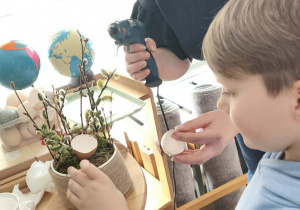 Dzieci przyklejają wydmuszki pod kontrola mamy Zosi