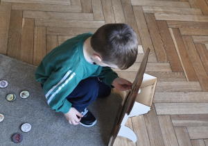 Na zdjęciu widzimy dziecko, które wkłada kartonik do "Głodomorka".