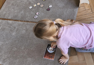 Na zdjęciu widzimy dziecko, które układa kartonik na zdjęciu przedstawiającym kawę - produktu, którego psy nie mogą pić.