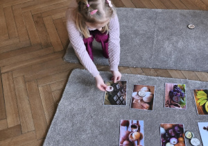 Na zdjęciu widzimy dziecko, które układa kartonik na zdjęciu przedstawiającym czekoladę - produktu, którego psy nie mogą jeść.