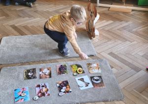 Na zdjęciu widzimy dziecko, które układa kartonik na zdjęciu przedstawiającym mleko - produktu, którego psy nie mogą pić.