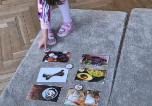 Na zdjęciu widzimy dziecko, które układa kartonik na zdjęciu przedstawiającym cebulę - produktu, którego psy nie mogą jeść.