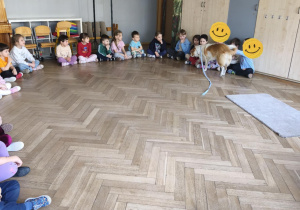 Na zdjęciu widzimy psa, który głaskany jest przez dzieci.