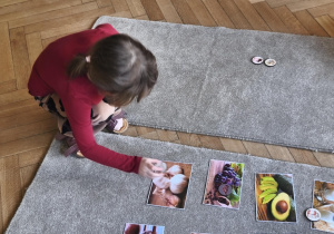 Na zdjęciu widzimy dziecko, które układa kartonik na zdjęciu przedstawiającym czosnek - produktu, którego psy nie mogą jeść.