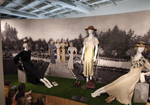 Na zdjęciu widzimy dzieci, które patrzą na eksponaty butów w Muzeum.