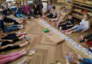 Dzieci siedzące w kole, a obok nich dwie różne skarpetki. Wspólna zabawa ze śpiewem