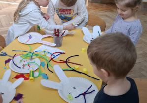 dzieci przy stołach tworzą królika z papieru