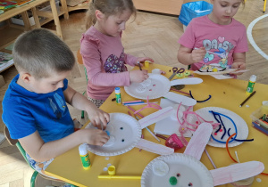dzieci przy stołach tworzą królika z papieru