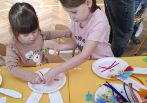 dziewczynki przy stołe tworzą królika z papieru