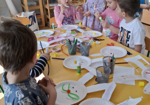 dzieci przy stołach tworzą królika z papieru