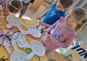 dzieci przy stołach tworzą królika z papieru
