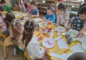 dzieci przy stołach tworzą królika z papieru