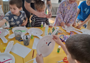 dzieci przy stołach tworzą królika z papieru