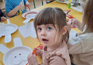 dzieci przy stołach tworzą królika z papieru