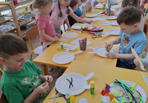 dzieci przy stołach tworzą królika z papieru