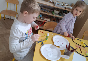 dzieci przy stołach tworzą królika z papieru