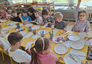 dzieci siedzą przy stole. na nim leżą materiały plastyczne