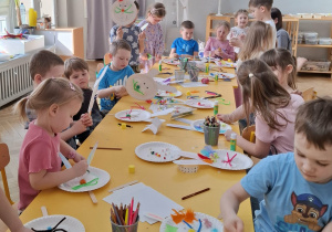 dzieci przy stołach tworzą królika z papieru