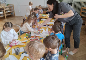 dzieci przy stołach tworzą królika z papieru