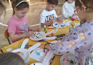 dzieci przy stołach tworzą królika z papieru