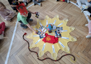 chłopiec w czerwonej koronie układa rzeczy na słoneczku