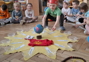 chłopiec w czerwonej koronie układa rzeczy na słoneczku