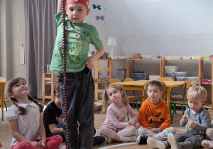 chłopiec w czerwonej koronie trzyna sznurek z koralikami