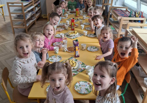 dzieci siedzą przy urodzinowym stole