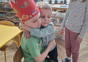 mały chłopiec przytula chłopca w czerwonej koronie