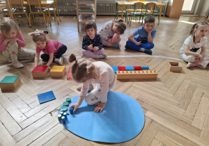 Dzieci dekorują wspólną pisankę używając materiał rozwojowy