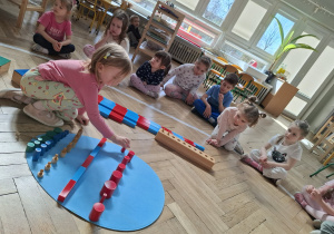 Dzieci dekorują wspólną pisankę używając materiał rozwojowy