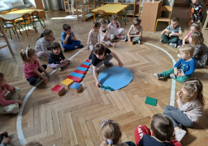 Dzieci dekorują wspólną pisankę używając materiał rozwojowy