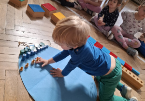 Dzieci dekorują wspólną pisankę używając materiał rozwojowy