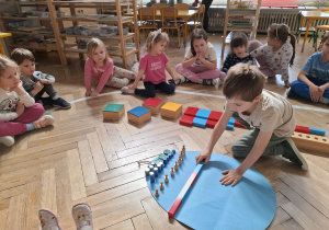 Dzieci dekorują wspólną pisankę używając materiał rozwojowy