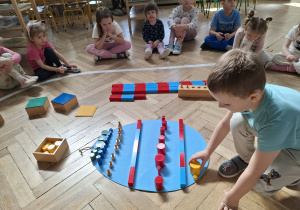 Dzieci dekorują wspólną pisankę używając materiał rozwojowy