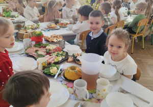 Zdjęcie przedstawia dzieci zgromadzone przy wielkanocnym stole.