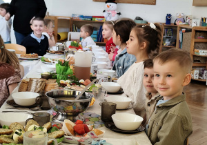 Zdjęcie przedstawia dzieci zgromadzone przy wielkanocnym stole.