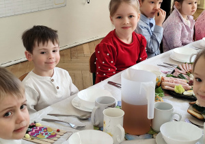 Zdjęcie przedstawia dzieci siedzące przy stole wielkanocnym.