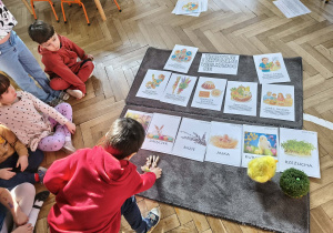 Na zdjęciu widzimy chłopca, który kładzie zajączki pod ilustracją.