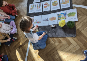 Na zdjęciu widzimy dziewczynkę, która kładzie bazie pod ilustracją.