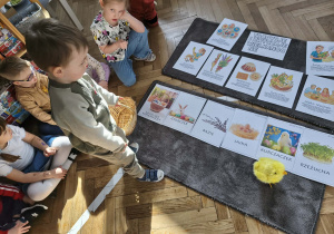 Na zdjęciu widzimy chłopca, który trzyma w ręku koszyk i kładzie go pod ilustracją koszyka.