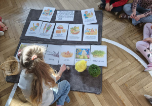 Na zdjęciu widzimy dziewczynkę, która kładzie jajka pod ilustracją.