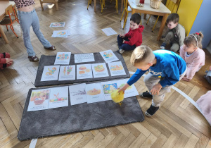 Na zdjęciu widzimy chłopca, który kładzie kurczątko pod ilustracją kurczaczka.