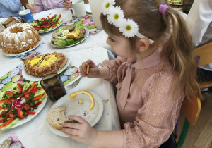 Na zdjęciu widzimy dziewczynkę, która je śniadanie wielkanocne.
