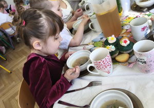 Na zdjęciu widzimy dzieci, które siedzą przy wielkanocnym stole i jedzą śniadanie.