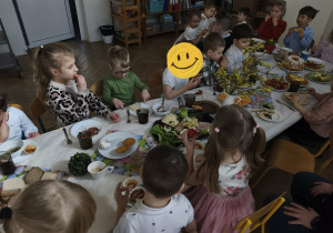 Na zdjęciu widzimy dzieci, które siedzą przy wielkanocnym stole i jedzą śniadanie.