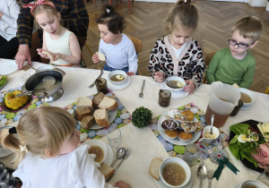 Na zdjęciu widzimy dzieci siedzące przy stole.