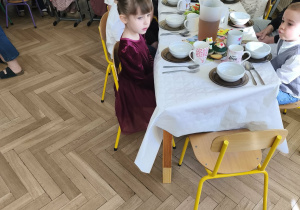 Na zdjęciu widzimy dzieci siedzące przy stole i jedzące śniadanie wielkanocne.